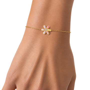 Gold chain bracelet with a coral flower charm on a wrist