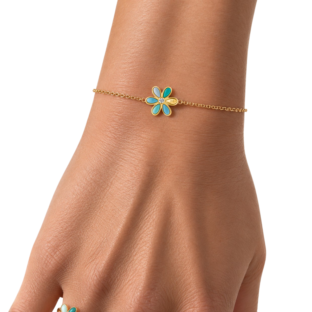 Gold bracelet with turquoise flower charm on thin chain, worn on wrist