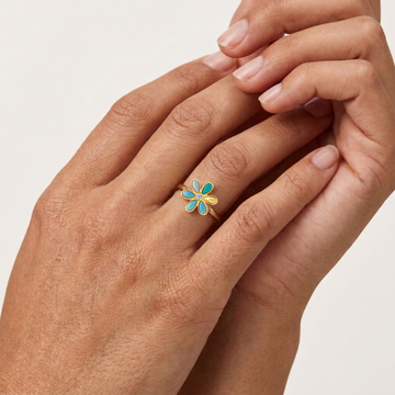 Gold-tone flower ring with turquoise and white enamel petals on finger