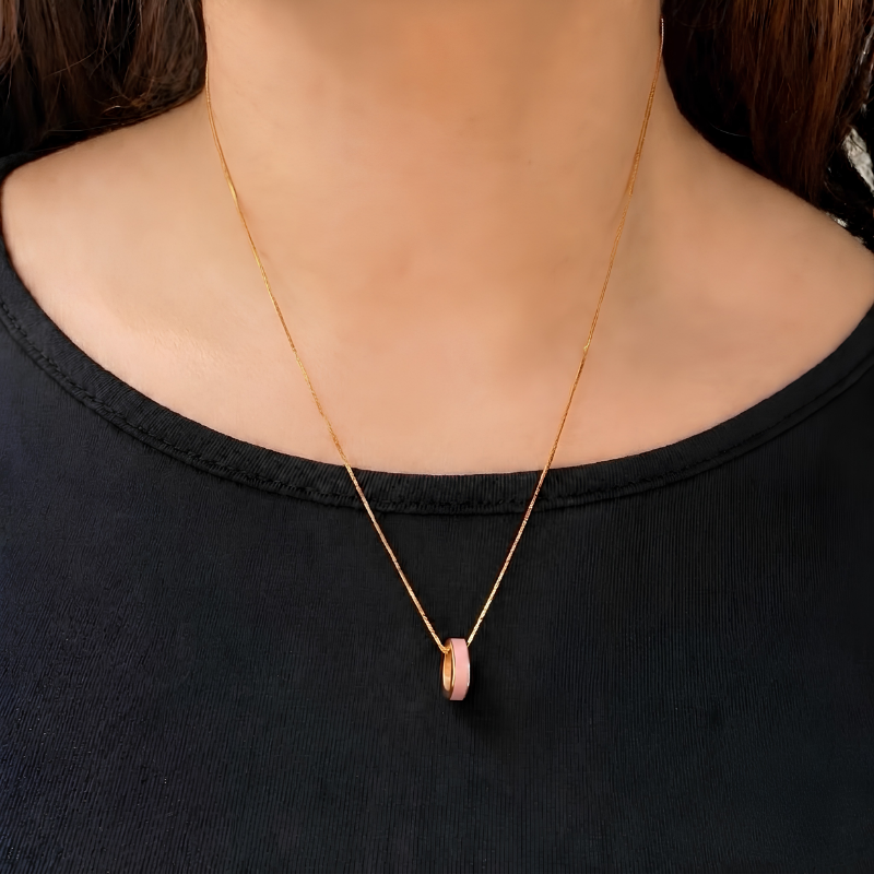 Woman wearing a necklace with a fondant pink ring pendant.