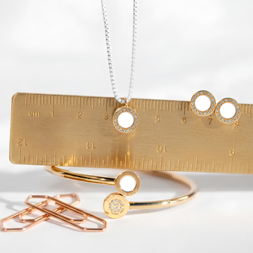 Gold circular jewelry with diamond pavé accents and a brass ruler.
