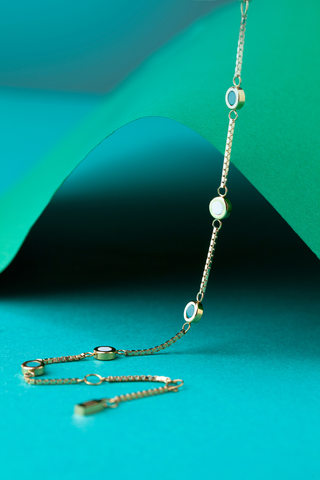 img-banner-Jason Hyde gold box-chain bracelet with white and turquoise circular station details.