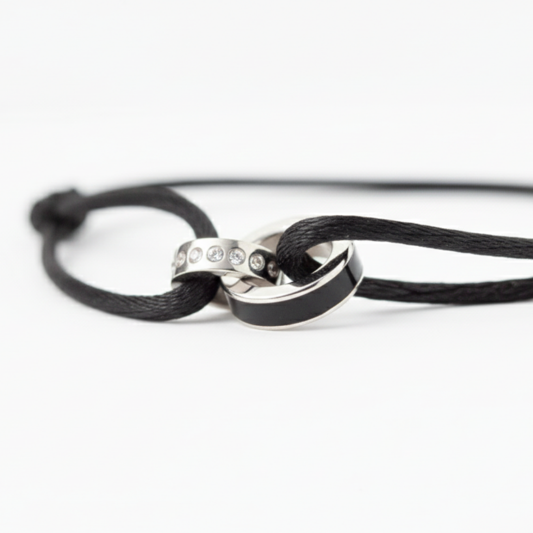 Macro shot of a black cord bracelet featuring interlocking silver rings