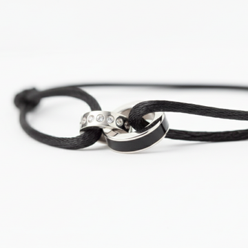 Macro shot of a black cord bracelet featuring interlocking silver rings