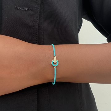 Close-up of a woman's wrist wearing a thin turquoise cord bracelet 