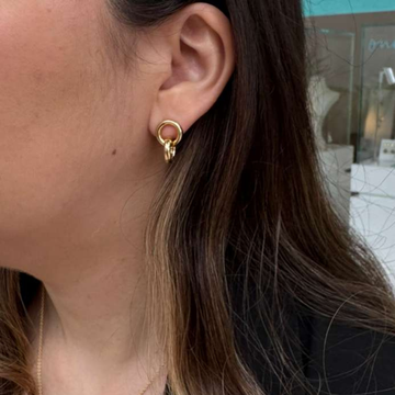 Close-up of a woman wearing a gold interlocking double ring earring