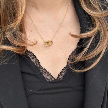 Close-up of a gold interlocking double circle necklace worn by a woman 