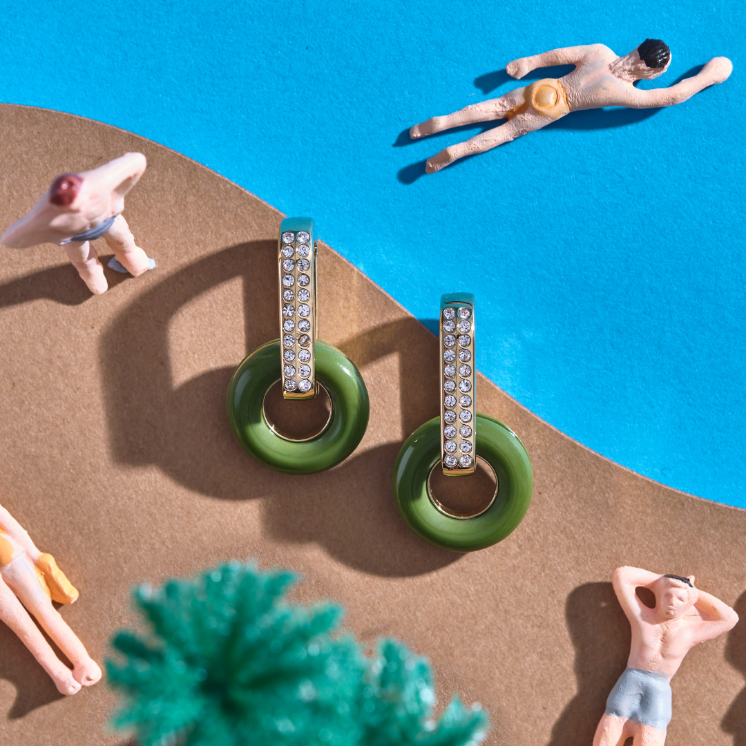 Green Lifesaver earrings by Jason Hyde, resting on a miniature sandy beach