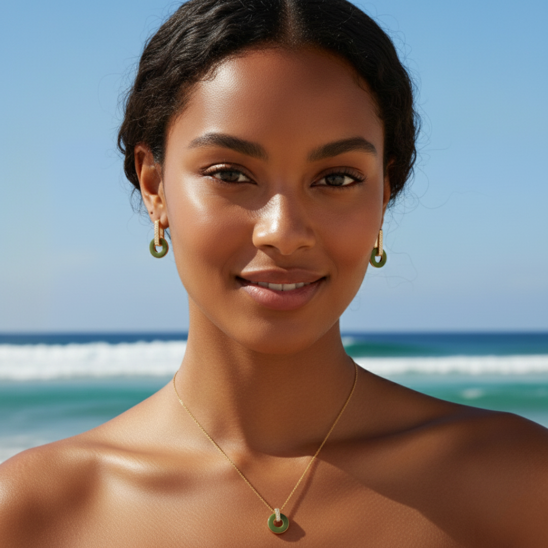 Model wearing a gold-plated necklace and matching hoop earrings with olive green enamel accents