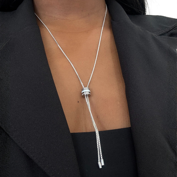 A woman wearing a silver lariat-style necklace with a white pendant 