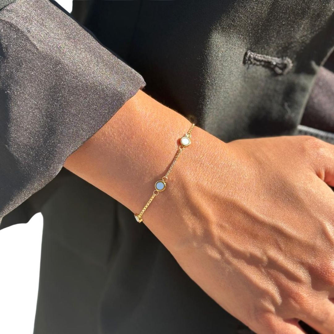 Gold chain bracelet with whiteand powder blue chips on wrist