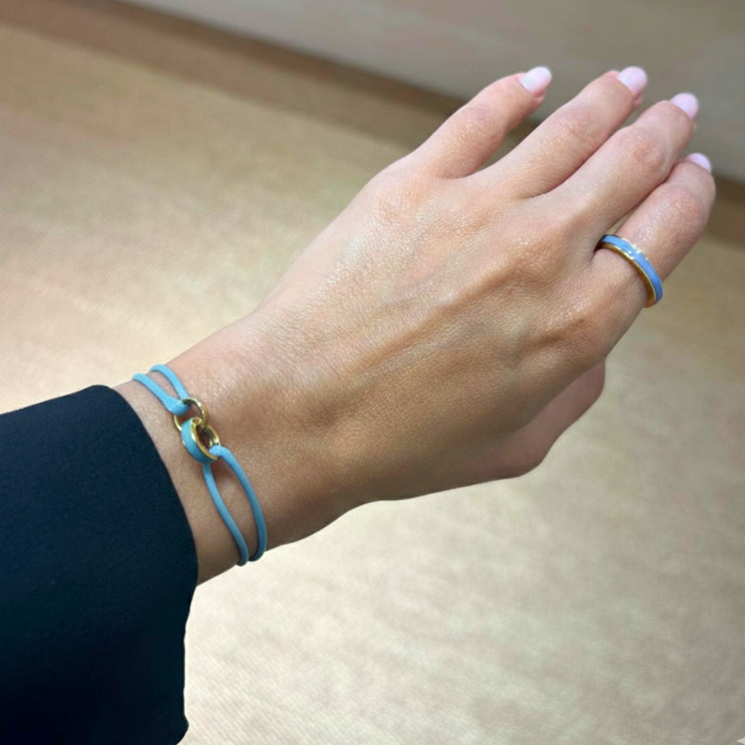 Jason Hyde powder blue cord bracelet with gold clasp on a woman's hand