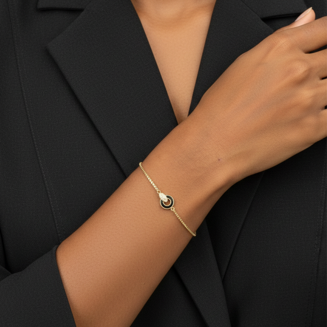 Gold-tone bracelet for women featuring an interlocking black enamel circle and pave zirconia accent.
