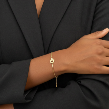 Dainty gold and beige enamel bracelet with sparkling crystal details worn by a model.