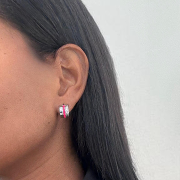 Silver-finished huggie hoop earrings with pink enamel and pavé crystals on a model.