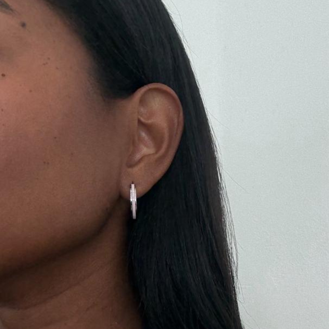 Silver-tone earrings featuring a sleek pink stripe detail, shown on a model's ear.