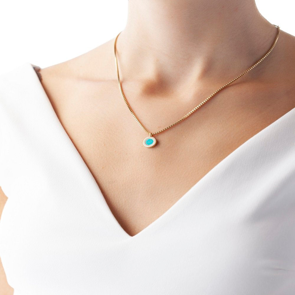 Delicate gold chain necklace with a small, round turquoise chip.