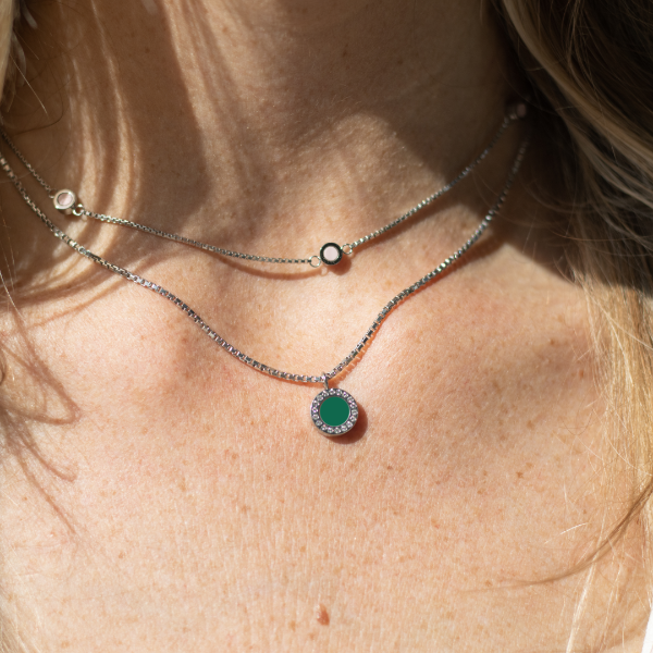 Neck wearing jason hyde delicate silver necklaces with white and green accents.