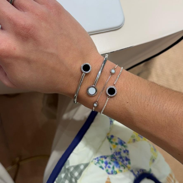 Layered jason hyde bracelets with black and white circular charms on wrist.