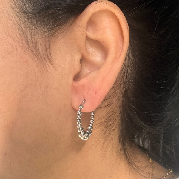 Stylish ear adorned with a Jason Hyde silver-tone beaded hoop earring.