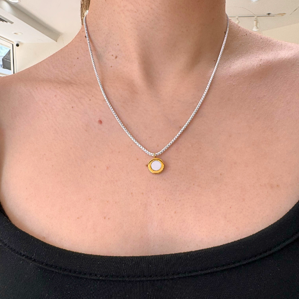Close-up of a person's décolletage wearing a Jason Hyde Ocean white necklace.