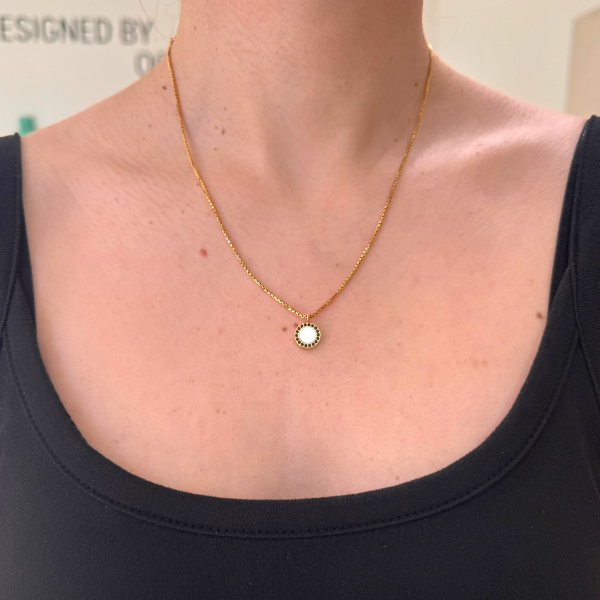 Gold-tone necklace with a white pendant featuring black zirconia border.