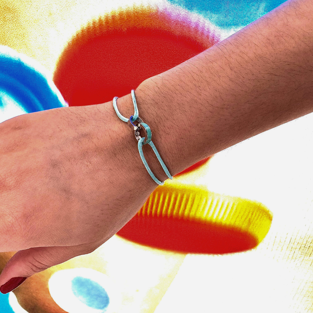 Turquoise cord bracelet with silver connector on wrist. 
