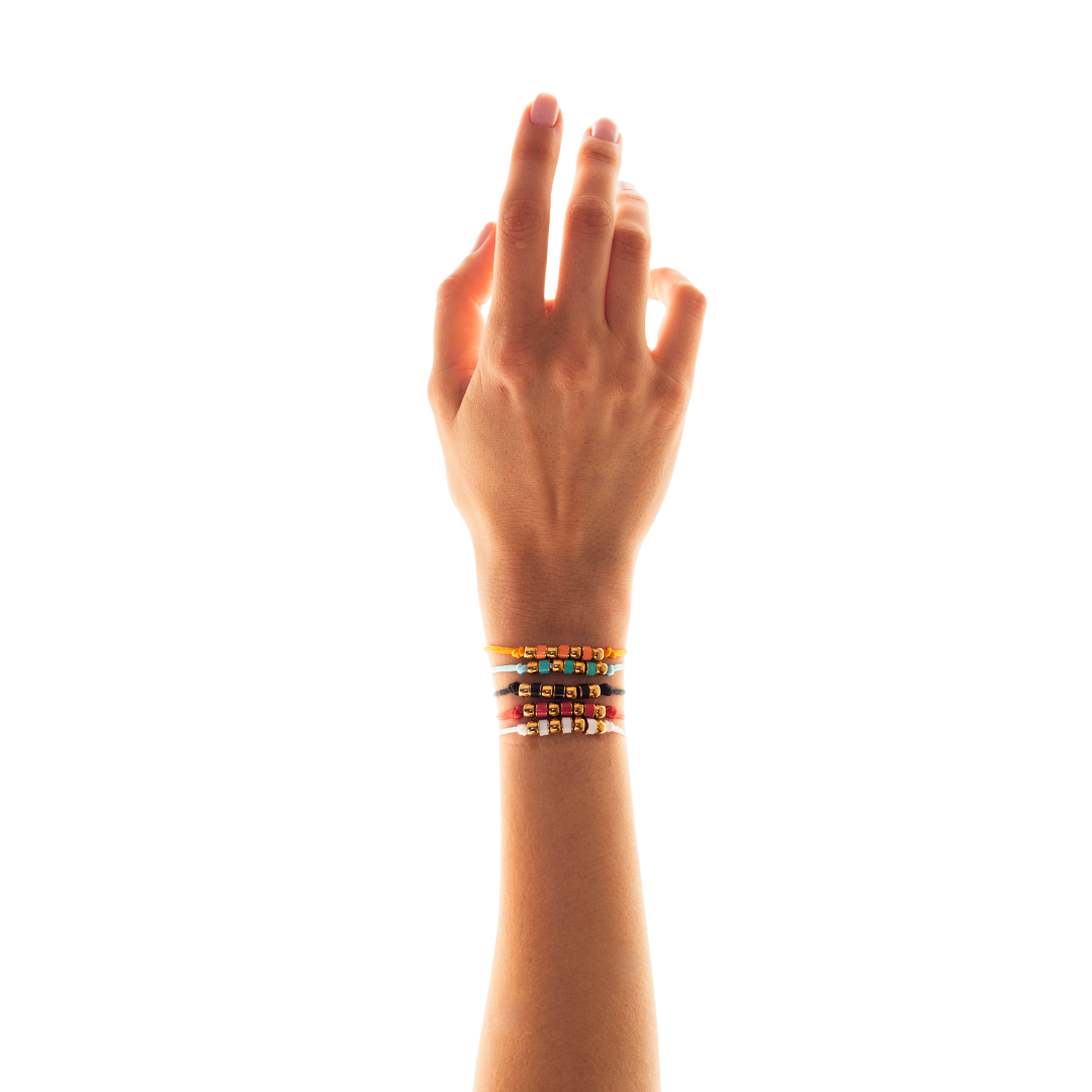 Hand and arm showcasing multiple Jason Hyde beaded bracelets in gold-tone.