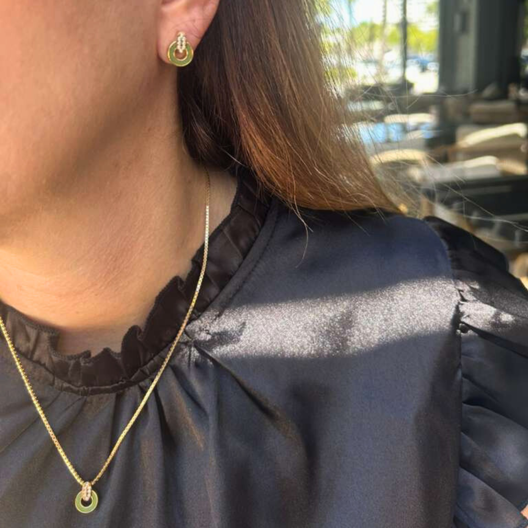 Gold necklace and matching green earrings on a woman.