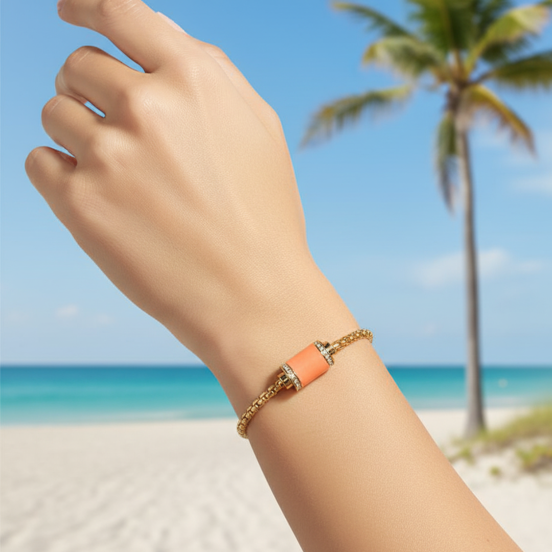 Gold chain bracelet with orange cylinder and zirconia accents on a wrist