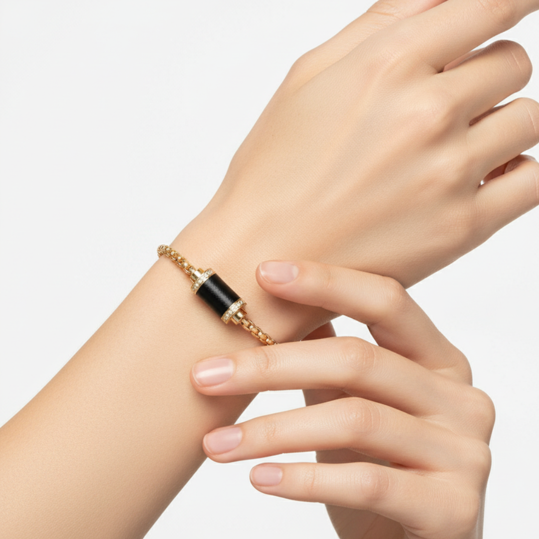 Gold chain bracelet with black cylinder and zirconia-pave end caps on a wrist