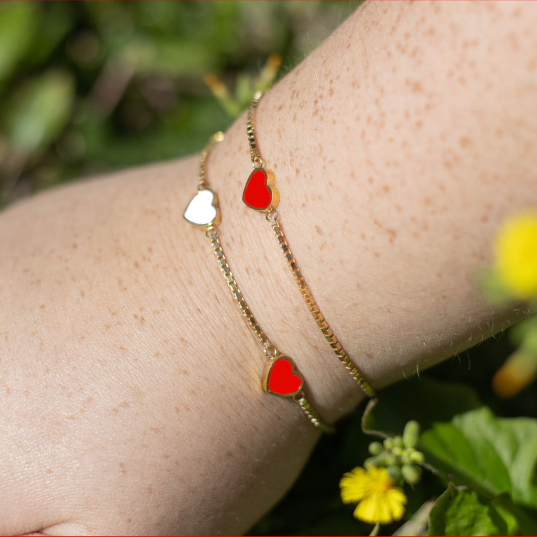 Sustainable gold jewelry bracelets by Jason Hyde with heart charms in red