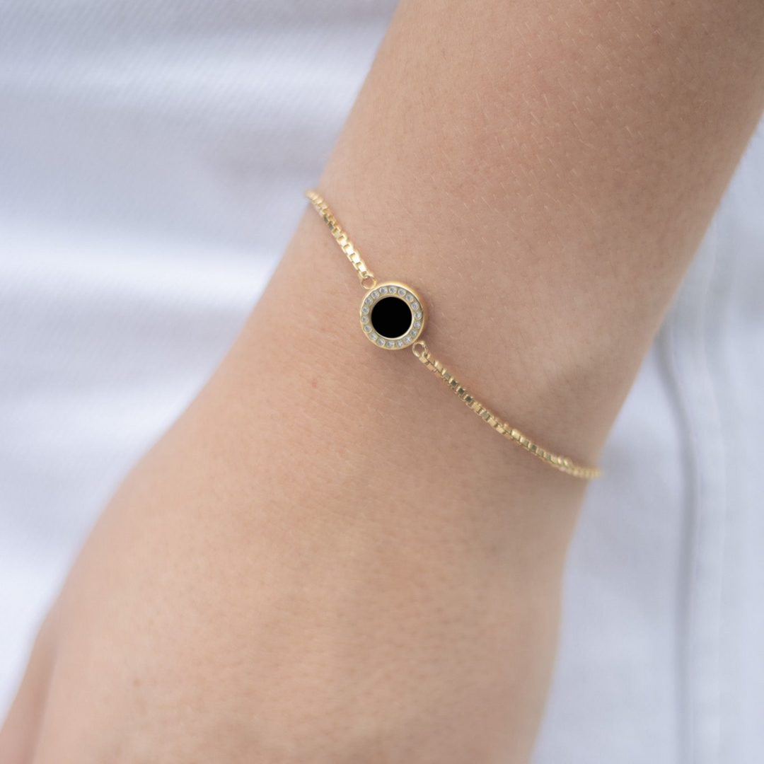 Gold bracelet with a round black chip surrounded by sparkling white zirconia