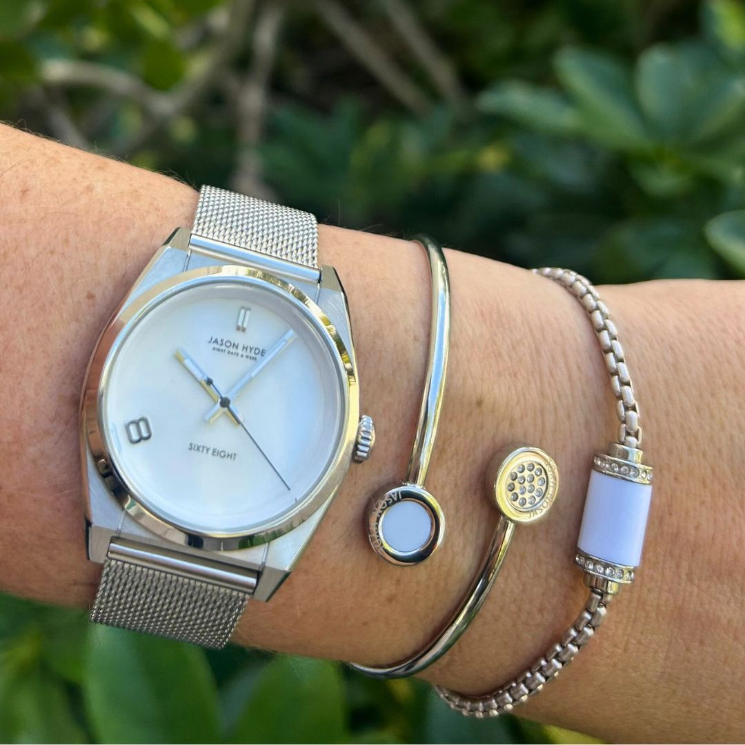 Wrist with a silver watch and two silver bracelets 