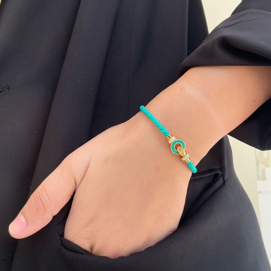 Gold and turquoise charm bracelet on a person's wrist.