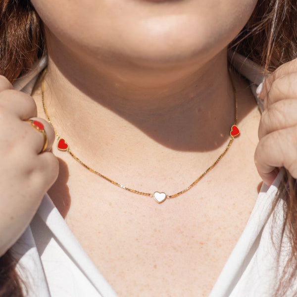 A Jason Hyde necklace with red and white heart charms on a woman's neck