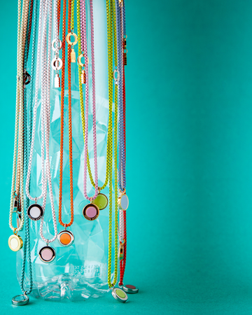 Clear plastic bottle with colorful necklaces on a teal background
