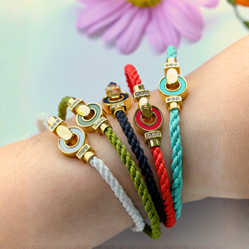Jason Hyde braided cord bracelets with colorful enamel charms and gold details.