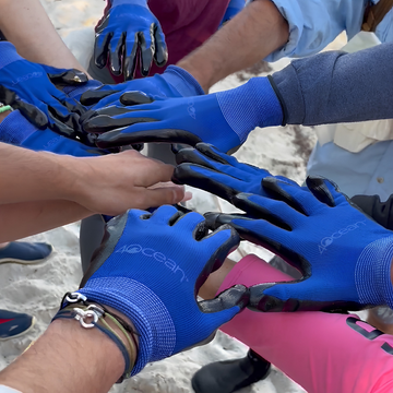 Team wearing 4ocean gloves participating in a Jason Hyde sustainable jewelry beach cleanup project.