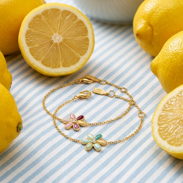 Two gold chain bracelets with flower pendants, surrounded by fresh lemons