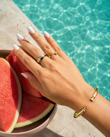 Woman's hand wearing Jason Hyde gold stacked ring and a open bangle