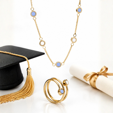 Jason Hyde gold graduation jewelry set with necklace and rings beside diploma and graduation cap