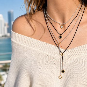 Woman wearing stacked Jason Hyde silver and black cord pendant necklaces.