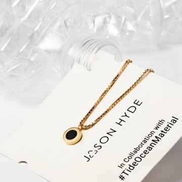 Gold necklace with black pendant inside a plastic bottle by Jason Hyde.