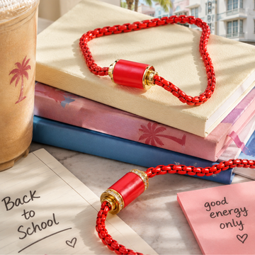 Red Jason Hyde mesh bracelets on notebooks with iced coffee.