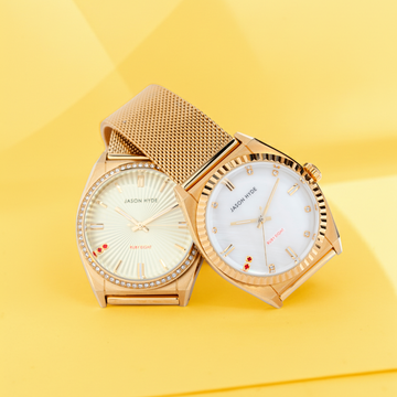 Two luxury Jason Hyde gold watches on a vibrant yellow background.