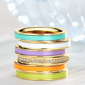 Stack of Jason Hyde gold rings with colorful enamel and crystal details.