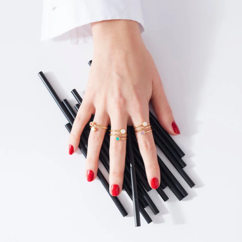 Woman wearing Jason Hyde gold stackable rings with colorful enamel details and modern styling.