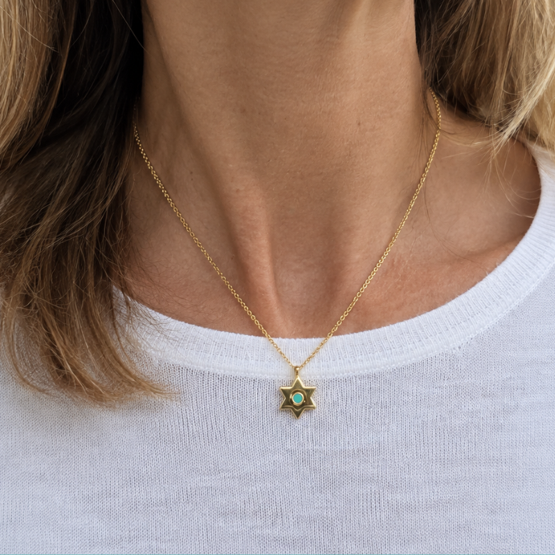 Close-up of a woman wearing the Jason Hyde gold star pendant necklace with a white top.