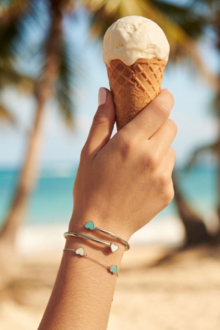 img-banner-A woman's hand holding a vanilla ice cream. Her wrist features a stack of two Jason Hyde silver bracelets